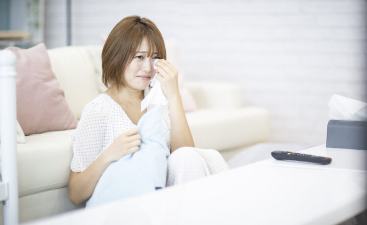 ソファに寄りかかって涙を拭う女性