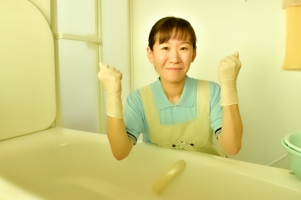 浴槽の横でエプロンと手袋を着用した女性がガッツポーズをしている写真